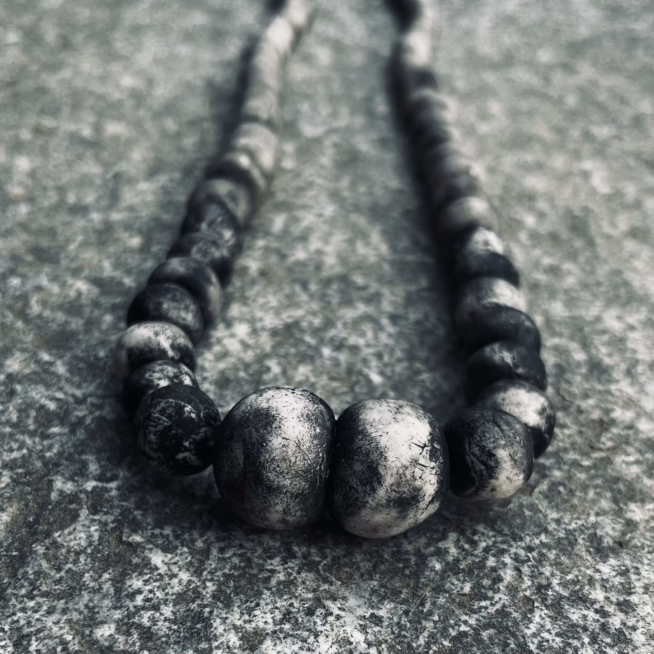 Handmade eggshell porcelain necklace photographed on natural stone by Italian contemporary jewelry artist Patrizia Giachero